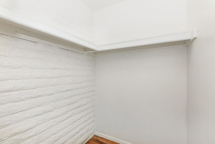 Bright and spacious walk-in closet with modern white walls and ample shelving.