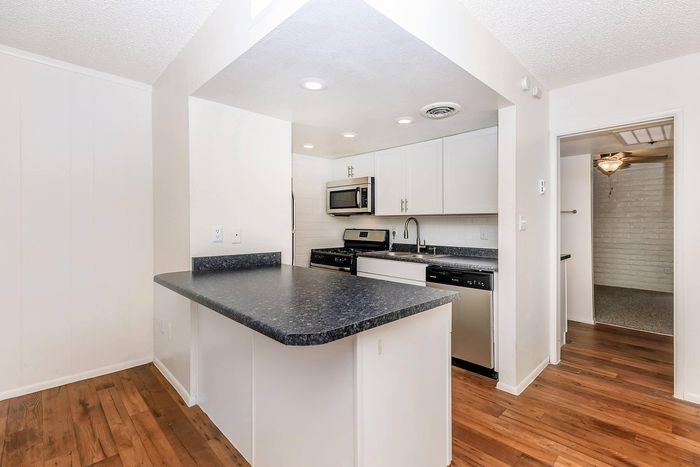 Bright and modern kitchen featuring sleek countertops, stainless steel appliances, and elegant wood flooring.