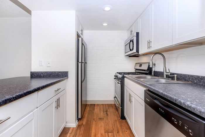 Modern kitchen with sleek stainless steel appliances, elegant white cabinetry, and beautiful hardwood floors.