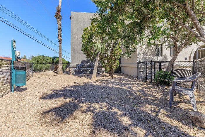 Inviting outdoor pet-friendly area with shady trees, a convenience station, and seating, perfect for relaxation in a serene setting.
