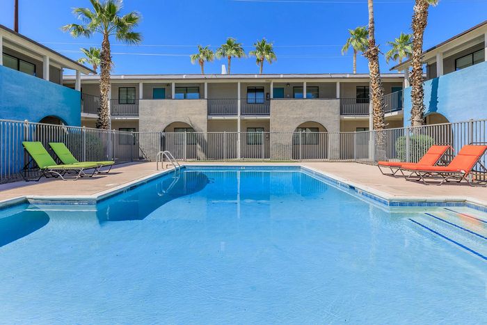 Inviting outdoor pool area surrounded by palm trees and colorful lounge chairs, perfect for relaxation and leisure.