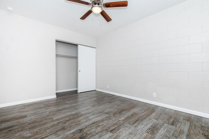 Bright and airy room with elegant wood flooring, ceiling fan, and a spacious closet, perfect for a cozy bedroom setup.