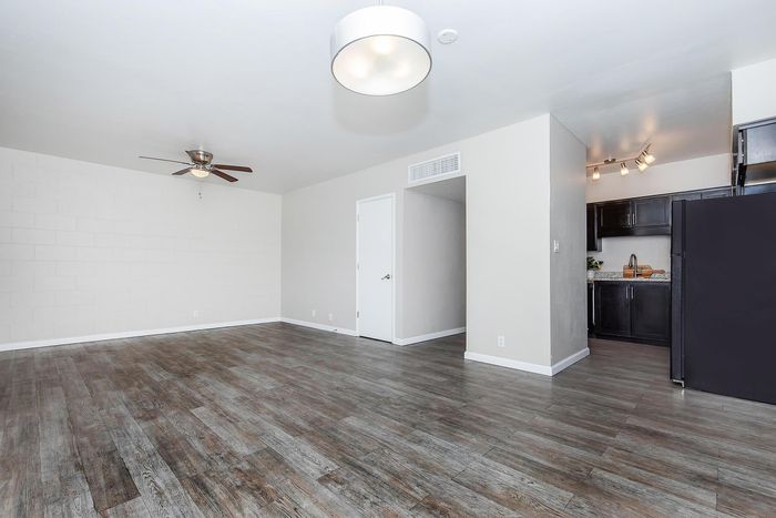 Spacious modern living area with elegant hardwood floors, stylish lighting, and an open kitchen with sleek dark cabinets.