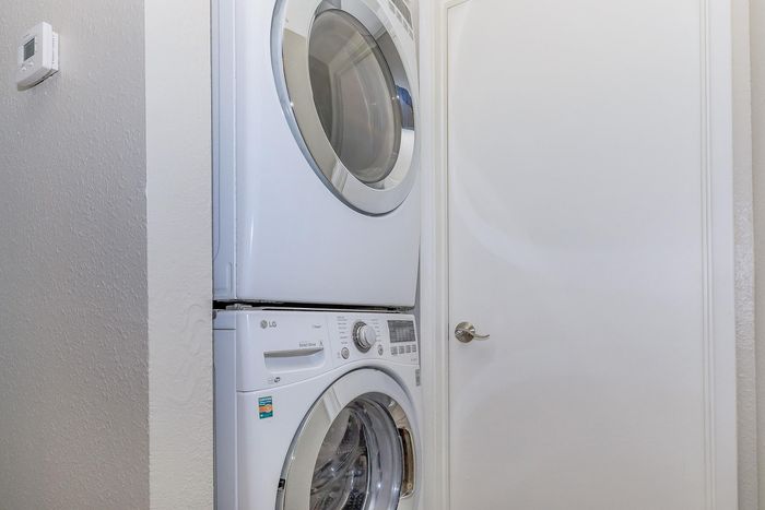 Modern apartment laundry area with stacked washer and dryer, featuring sleek design and energy-efficient appliances.