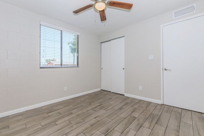 Bright and airy room with modern wood flooring, elegant ceiling fan, and large window offering natural light.