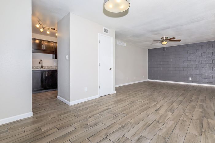 Open-plan living area with elegant wood-look tile flooring and modern kitchen featuring dark cabinetry and contemporary lighting.