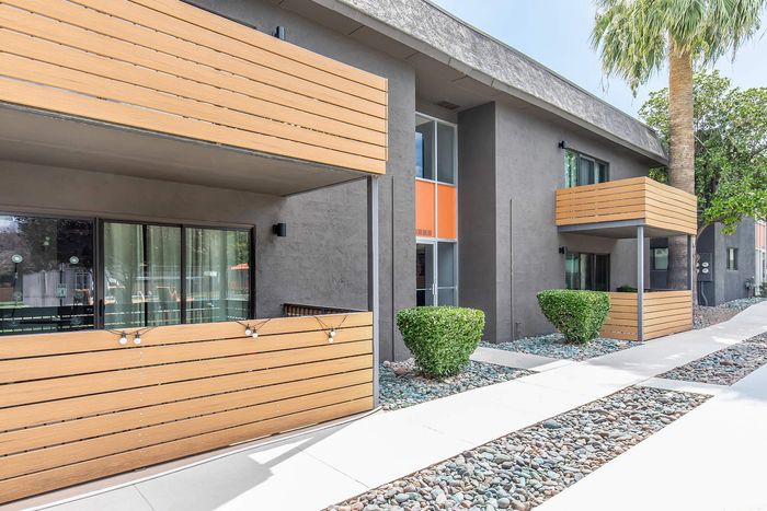 Contemporary apartment exterior with stylish wooden balconies and lush greenery, offering a serene and inviting atmosphere.
