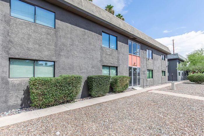 Contemporary apartment building exterior with sleek design and manicured landscaping under a clear blue sky.