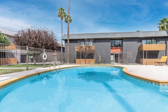 Inviting outdoor pool area with crystal-clear water, surrounded by modern apartment building featuring stylish wood accents and lush landscaping.