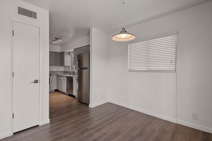 Modern apartment with sleek gray cabinetry, stainless steel appliances, and elegant wood flooring, featuring ambient lighting and spacious layout.