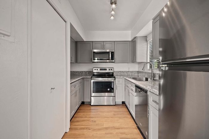 Modern kitchen with sleek stainless steel appliances, granite countertops, and elegant grey cabinetry.