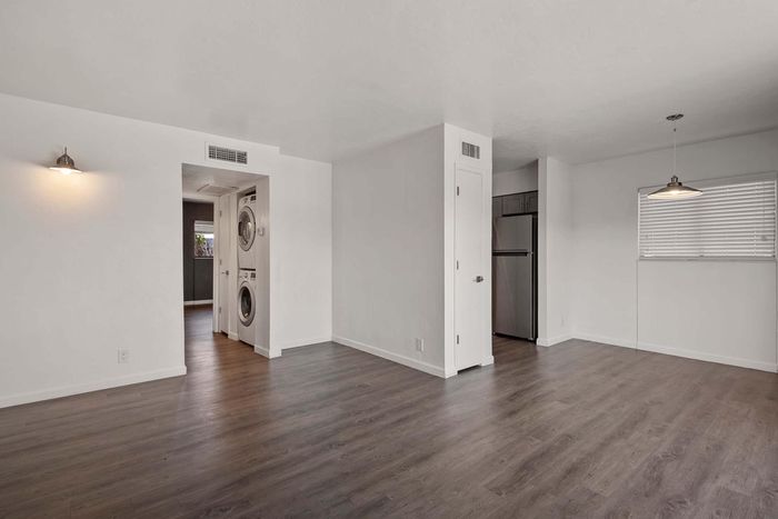 Bright and modern apartment with sleek wood floors, in-unit washer and dryer, and stylish kitchen area with stainless steel fridge.