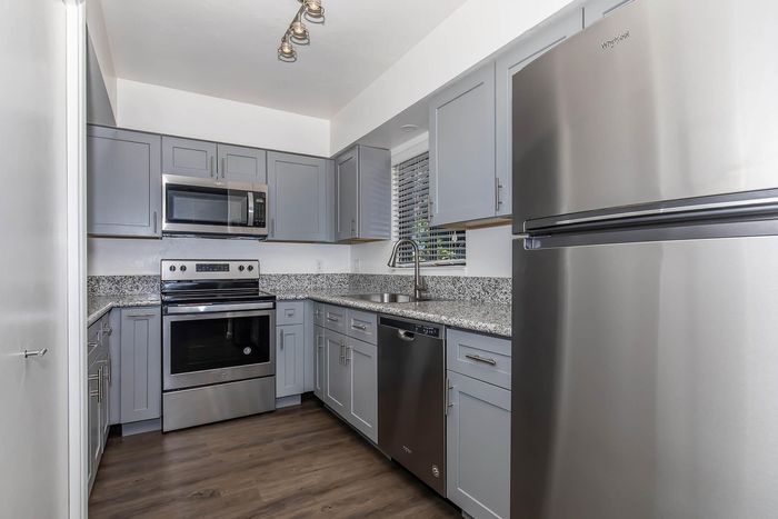 Modern kitchen with sleek stainless steel appliances, elegant gray cabinetry, and granite countertops.