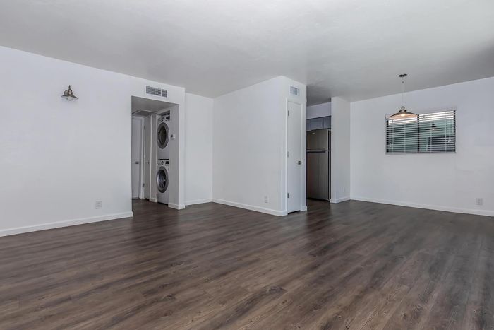 Spacious open-concept apartment with modern dark wood flooring, in-unit washer and dryer, and ample natural light.