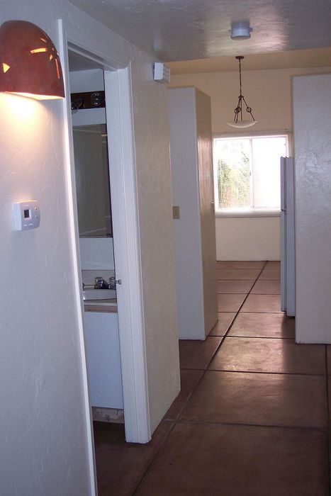 Chic hallway view showcasing elegant tile flooring, soft wall lighting, and a glimpse of modern fixtures in a stylish apartment setting.