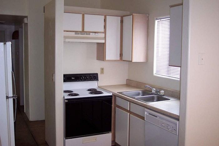 Bright and cozy kitchen with compact layout, featuring an electric stove, spacious countertops, and natural light through a large window.