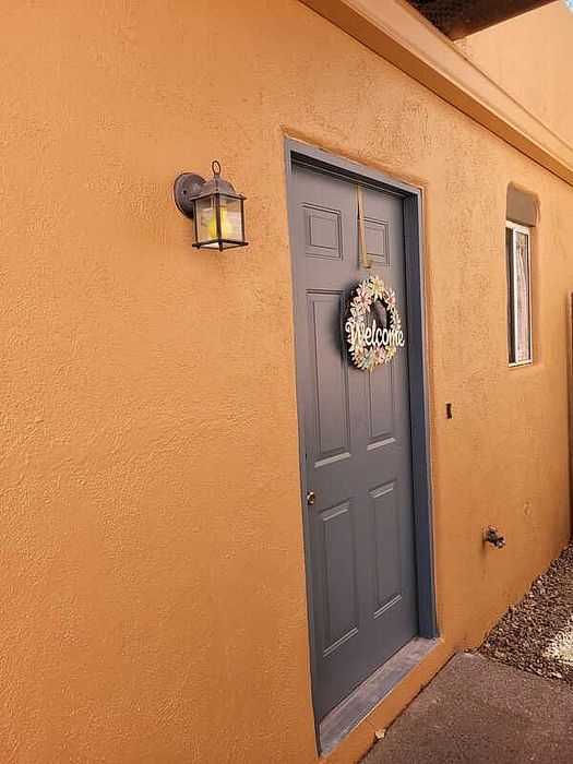 Charming entryway with a warm terracotta exterior wall and elegant blue door adorned with a welcoming floral wreath.