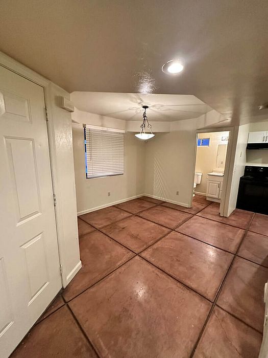 Cozy apartment with warm-toned tile floors, modern lighting, and a welcoming kitchen area.