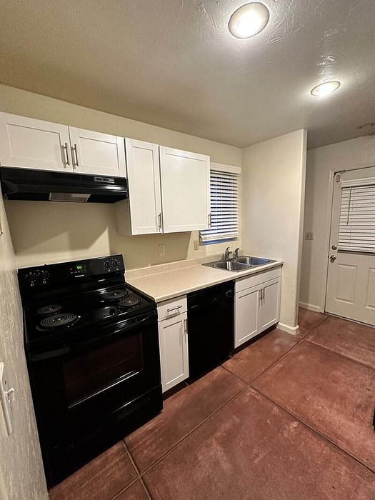 Modern kitchen with sleek black appliances, spacious countertops, and elegant white cabinetry, perfect for cooking enthusiasts.