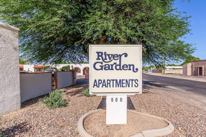 Inviting entrance to River Garden Apartments, highlighted by lush greenery and a welcoming sign.