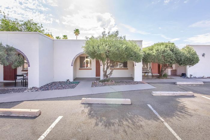 Charming apartment exterior with arched entryways and lush greenery, offering a warm and inviting atmosphere.