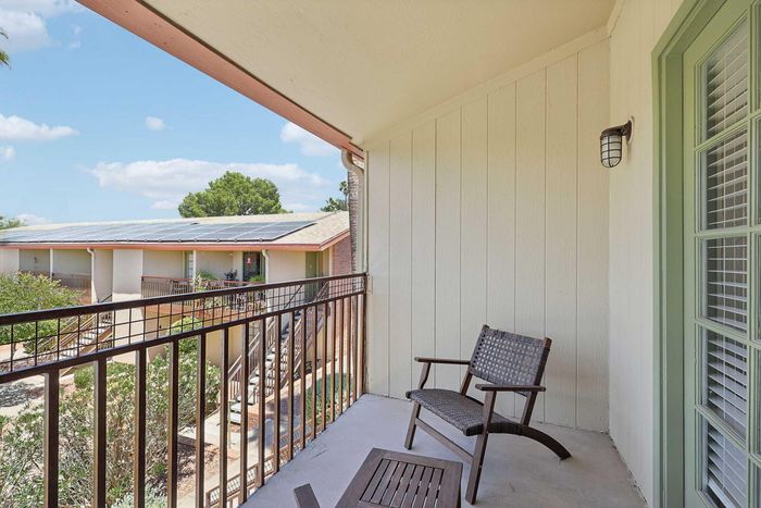 Charming balcony view showcasing comfortable seating and scenic rooftop landscape under blue skies.