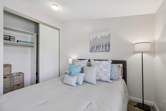 Bright and cozy bedroom featuring elegant decor, plush pillows, a stylish floor lamp, and ample closet space.