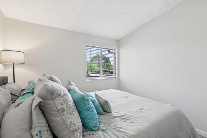 Serene bedroom with plush pillows, soft lighting, and a window view of lush greenery.
