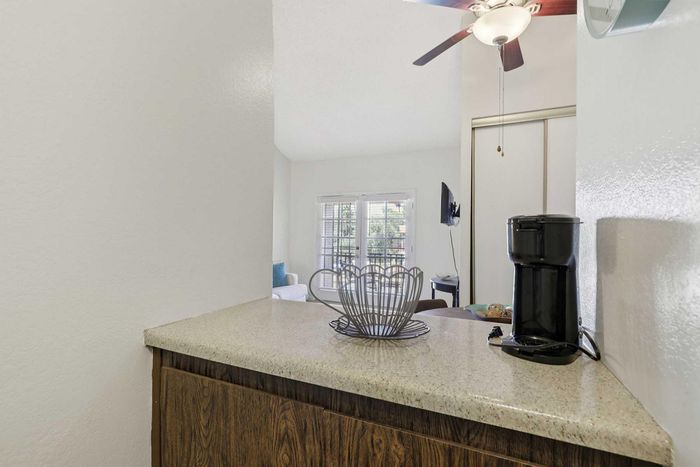 Inviting modern kitchen counter with sleek coffee maker and decorative elements leading to a bright living area with large windows.