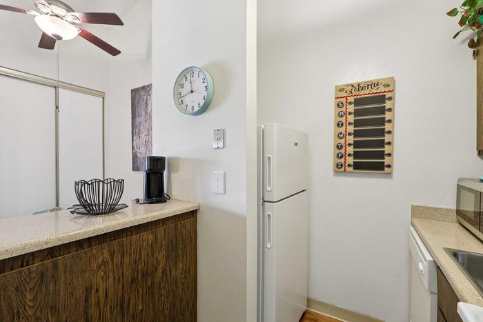 Charming kitchen nook with modern amenities, featuring a sleek refrigerator, stylish wall-mounted clock, and a convenient coffee maker.