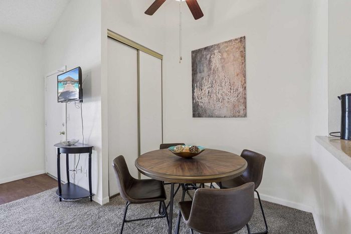 Charming dining area with a round wooden table, four stylish leather chairs, and elegant decor; perfect for cozy meals.