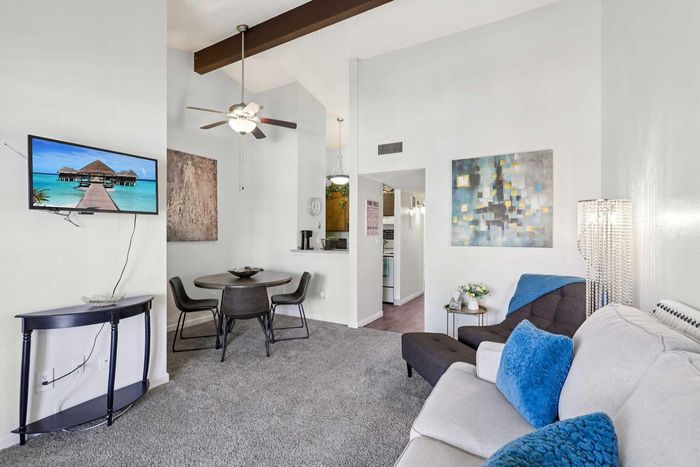Charming living room with high ceilings, modern decor, cozy seating, and a mounted TV, offering a welcoming and stylish ambiance.