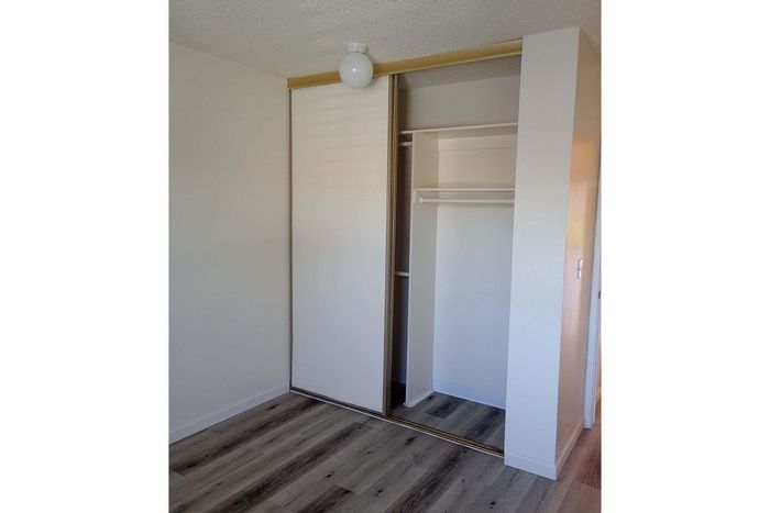 Modern apartment closet with sliding doors, offering ample storage space and sleek wood flooring.