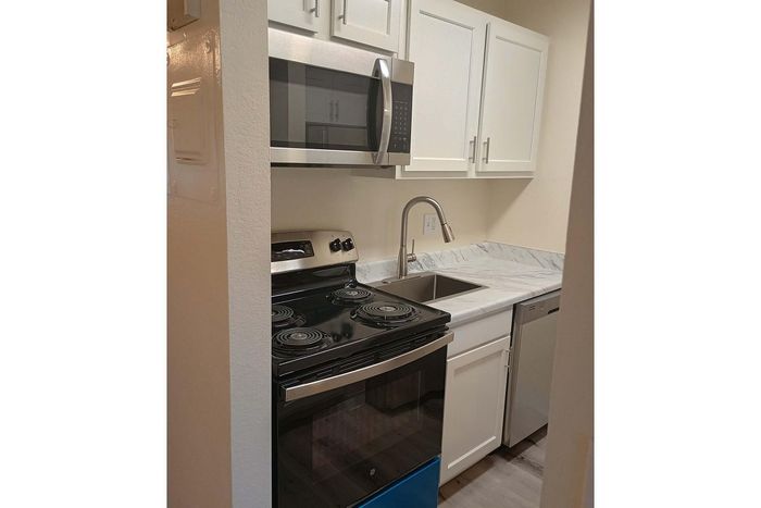 Modern kitchen with sleek stainless steel appliances, elegant white cabinets, and a stylish marble countertop.