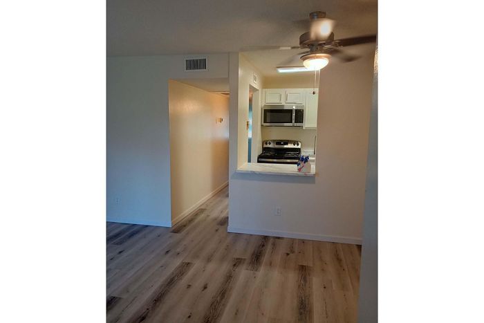 Bright apartment featuring modern kitchen with stainless steel appliances, open floor design, and elegant ceiling fan.
