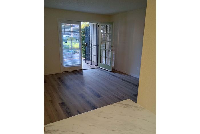 Bright open room with elegant hardwood flooring and a welcoming view through French doors leading to a lush garden.