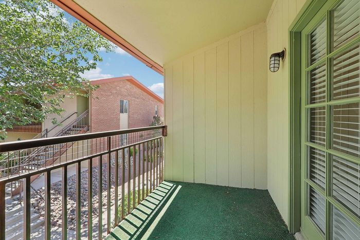 Inviting balcony with green accents overlooking a charming courtyard, perfect for relaxing and enjoying the outdoors.