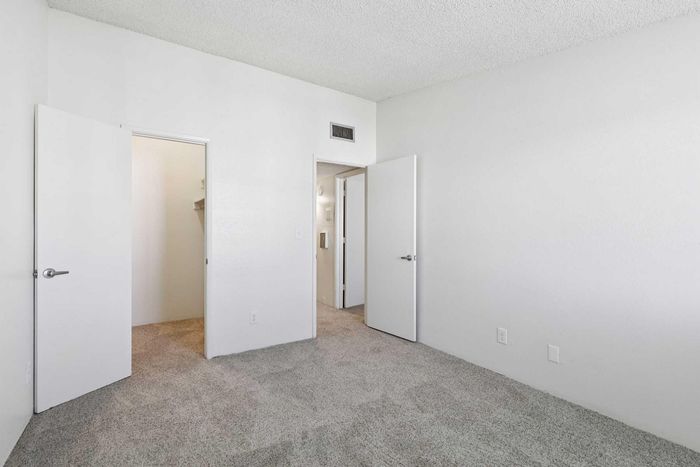 Bright and airy bedroom featuring plush carpeting, a walk-in closet, and modern finishes.