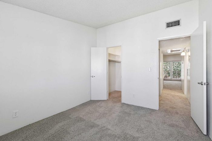 Inviting bedroom with plush carpet, open closet, and bright natural light from adjacent room, perfect for personal retreat.