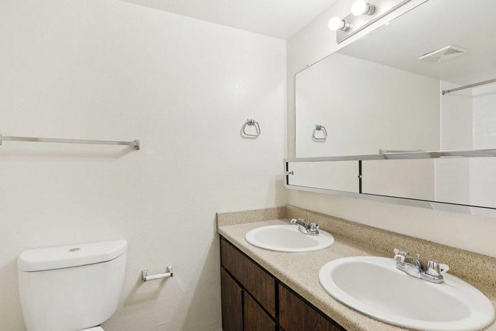 Bright and modern bathroom featuring dual sinks, elegant lighting, and sleek fixtures.