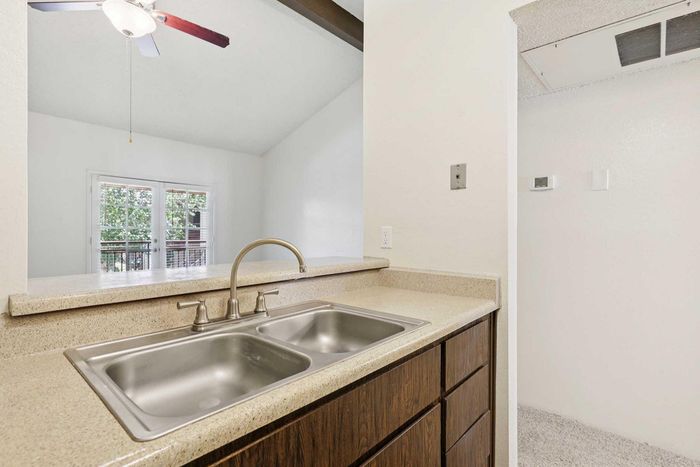 Modern kitchen space with sleek dual sink, elegant countertops, and scenic view of a balcony framed by large windows.