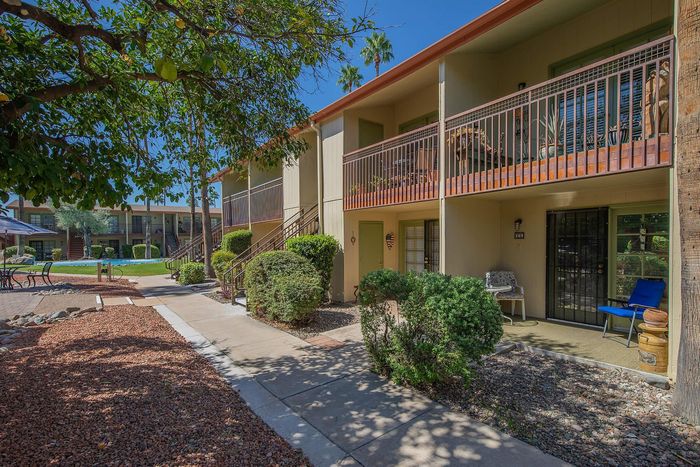 Charming apartment complex with lush greenery, cozy patios, and a serene outdoor seating area.