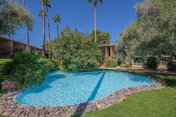 Charming apartment complex with lush greenery and a sparkling pool, perfect for relaxation under the palm trees.