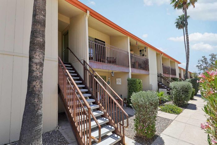 Charming apartment exterior with lush landscaping, featuring a welcoming staircase leading to the private balcony.
