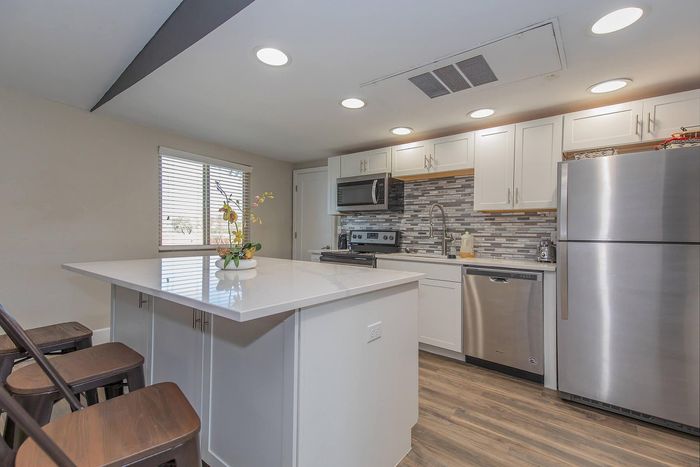 Modern kitchen featuring sleek stainless steel appliances, a stylish tile backsplash, and a spacious island with bar stools.