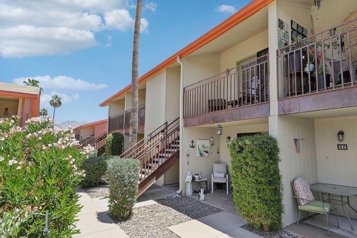 Charming townhouse exterior with vibrant garden views, inviting balconies, and scenic palm tree settings.