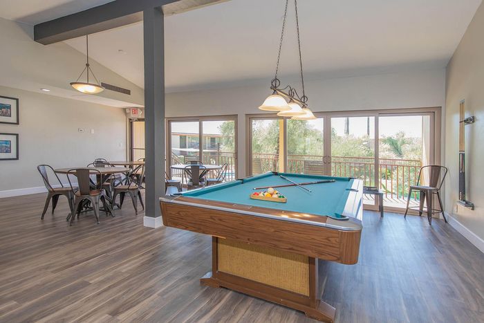 Contemporary recreation room featuring a chic billiards table, elegant seating area, and large windows offering scenic views.