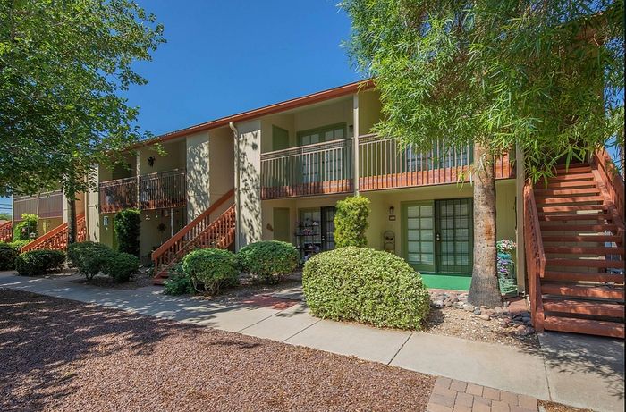 Charming two-story apartment building with lush greenery, inviting staircases, and sunny balconies, perfect for enjoying peaceful outdoor moments.