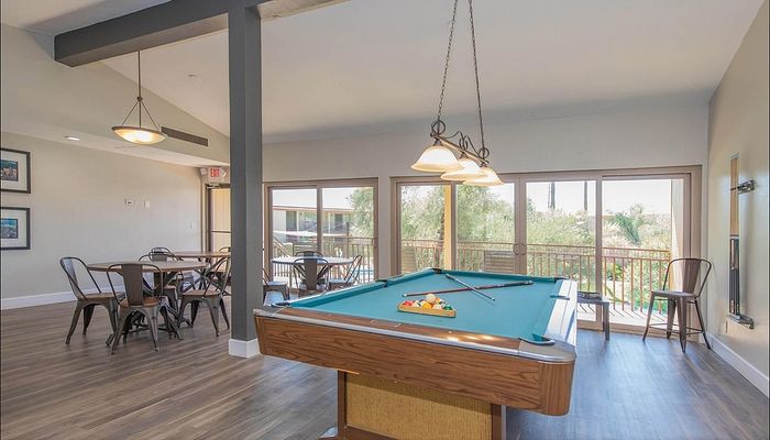 Elegant recreation room featuring a billiard table, stylish dining set, and floor-to-ceiling windows with abundant natural light.