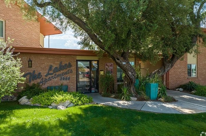 Charming exterior of The Lakes Apartments, featuring well-maintained landscaping with lush greenery and mature trees.